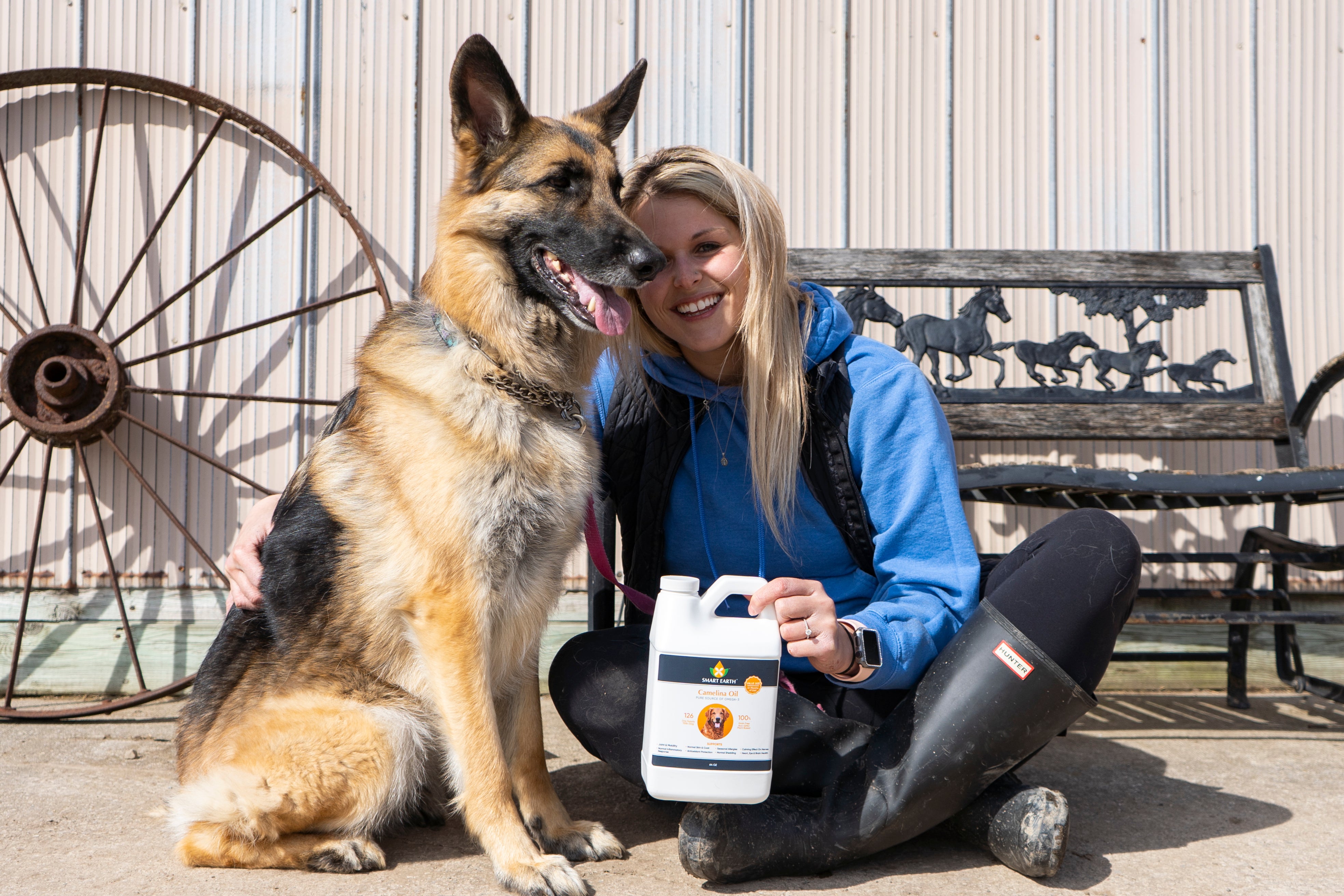 Woman with a German Shepherd dog holding a product container outdoors.