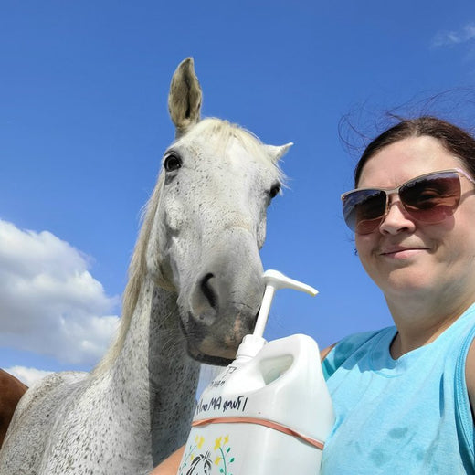 Angie H. outdoors with her grey horse and a jug fitted with a pump