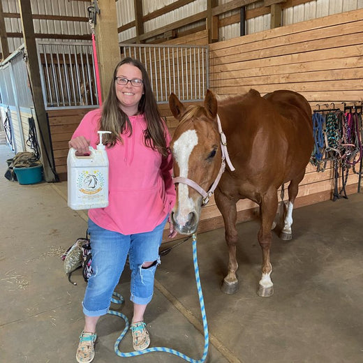 Heidi B. in the barn aisle with her chestnut mare and a jug